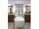 Modern bathroom featuring dual vanities, a soaking tub, and natural light from the window at 64 Tapadero Ln, Las Vegas, NV 89135