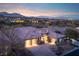 Beautiful single-story home with a brick driveway and lush landscaping against a mountain backdrop at sunset at 64 Tapadero Ln, Las Vegas, NV 89135