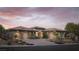 Stunning home showcasing a three-car garage, desert landscaping, and inviting curb appeal at dusk at 64 Tapadero Ln, Las Vegas, NV 89135