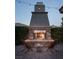 Inviting outdoor fireplace with stone surround, chairs, and string lights for cozy evenings outdoors at 64 Tapadero Ln, Las Vegas, NV 89135