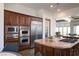 Gourmet kitchen featuring custom cabinets, stainless steel appliances, and a center island cooktop at 64 Tapadero Ln, Las Vegas, NV 89135