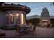 Charming outdoor patio with a dining table, chairs, fireplace, string lights, and view to kitchen inside at 64 Tapadero Ln, Las Vegas, NV 89135