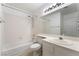 Bright bathroom featuring a shower-tub combo, white tiled walls, and a large vanity mirror at 6871 Tamarus St # 204, Las Vegas, NV 89119