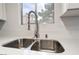 Close-up of kitchen sink with stainless steel double basin, modern faucet, and speckled countertops at 6871 Tamarus St # 204, Las Vegas, NV 89119