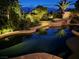 A beautiful backyard pool and spa are surrounded by lush landscaping and reflected lighting at nighttime at 8221 Bay Dunes St, Las Vegas, NV 89131