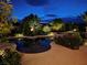 A beautiful backyard pool and spa are surrounded by lush landscaping and ambient lighting at nighttime at 8221 Bay Dunes St, Las Vegas, NV 89131