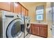 Laundry room featuring a washer, dryer, storage cabinets, and a window at 9192 Moose Country Pl, Las Vegas, NV 89178