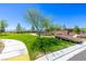 Walking path through lush green common area featuring desert landscaping and a stone wall at 12404 Aster Hills Ave, Las Vegas, NV 89138