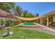 Landscaped backyard with a swimming pool, covered patio, rock features, and mature trees at 1905 Dakota Hills Ave, Las Vegas, NV 89123