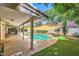 Backyard with a swimming pool, covered patio, artificial turf, and mature trees at 1905 Dakota Hills Ave, Las Vegas, NV 89123