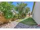Beautiful backyard featuring artificial grass, rockscaping, and mature trees at 1905 Dakota Hills Ave, Las Vegas, NV 89123