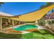 Backyard with covered outdoor seating, a pool, lush landscaping, and shade sail at 1905 Dakota Hills Ave, Las Vegas, NV 89123