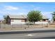 Charming single-story home featuring a two-tone exterior, fenced yard, and mature tree under a bright blue sky at 2440 Homestead Rd, Pahrump, NV 89048