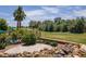 Serene backyard with rock waterfall, patio, mature landscaping, and green space view at 2505 Links Dr, Laughlin, NV 89029
