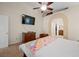 Bedroom featuring a TV, ceiling fan, arched doorway to bathroom and tan carpet at 2505 Links Dr, Laughlin, NV 89029