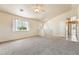 Bright living room with neutral carpet, a ceiling fan, and a large window providing ample natural light at 480 China St, Pahrump, NV 89048