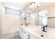 Bright bathroom featuring dual sinks, matte black fixtures, and a shower-tub combination with a white tile surround at 6260 Castle Kennedy St, Henderson, NV 89011
