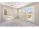 A bright bedroom with neutral walls and carpet, featuring multiple windows and a door to an outdoor balcony at 6260 Castle Kennedy St, Henderson, NV 89011
