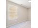 A simple bedroom with neutral paint and carpet, and a single window offering natural light at 6260 Castle Kennedy St, Henderson, NV 89011
