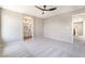 Large bedroom with neutral carpet, ceiling fan, and bathroom access at 6260 Castle Kennedy St, Henderson, NV 89011