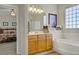 Relaxing bathroom with soaking tub, framed art, vanity with framed mirror, and an open view to the main bedroom at 6440 Bristlebird St, North Las Vegas, NV 89084