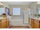 Bright bathroom featuring a soaking tub, glass shower, and double vanity with wood cabinets at 6440 Bristlebird St, North Las Vegas, NV 89084