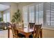 Cozy dining area featuring a wooden table, plantation shutters, and a decorative pineapple centerpiece at 6440 Bristlebird St, North Las Vegas, NV 89084