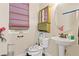Bathroom with a pedestal sink, uniquely decorated toilet, and a window with blinds, adding a personalized touch at 6714 Flamenco Ct, Las Vegas, NV 89139
