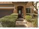 Close up of front door framed by lush landscaping leading to a two-car garage at 7630 Canyon Diablo Rd, Las Vegas, NV 89179