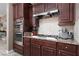 Close up on a kitchen featuring stainless steel double oven, hood, and granite countertops at 7630 Canyon Diablo Rd, Las Vegas, NV 89179