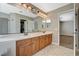 Double vanity with neutral countertops, warm wood cabinets, and large mirror at 7637 Good Fortune Ct, Las Vegas, NV 89139