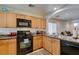 Functional kitchen with wood cabinetry and black appliances, showcasing a practical layout, with countertop and dining views at 7645 Interlace St, Las Vegas, NV 89149