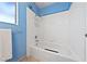 White tub and shower with blue walls, multiple shower heads, and white tile at 823 Schooner Dr, Henderson, NV 89015