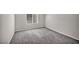 An empty bedroom features carpeted floors, a large window, and neutral paint, ready for customization at 9876 Magnus Ct, Las Vegas, NV 89178