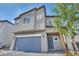 Two-story home featuring a gray exterior, a blue garage door, and a well-maintained front yard at 9876 Magnus Ct, Las Vegas, NV 89178