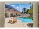 Poolside view of the home featuring a tiled roof and solar panels at 13 Dovetail Cir, Henderson, NV 89014