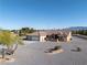 Wide shot of a desert home with gravel landscaping, a three-car garage, and a mountain view at 1361 Moose St, Pahrump, NV 89048