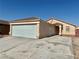 Exterior view of a tan single-story home with a large garage and desert landscaping at 2621 Blue Reef Dr, North Las Vegas, NV 89032