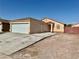 Exterior view of a tan single-story home with a large garage and desert landscaping at 2621 Blue Reef Dr, North Las Vegas, NV 89032