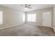Bright living room with a large window, neutral carpet, a ceiling fan, and a white front door at 3209 Cheltenham St, Las Vegas, NV 89129