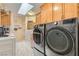Well-equipped laundry room features wooden cabinetry, a skylight, and modern washer and dryer units at 3231 Rebel Ave, Pahrump, NV 89048