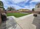 Spacious backyard featuring artificial grass, a BBQ, and an outdoor fireplace at 412 Orchid Oasis Ave, North Las Vegas, NV 89031