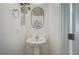 Powder room featuring a pedestal sink, decorative mirror, and modern fixtures at 412 Orchid Oasis Ave, North Las Vegas, NV 89031