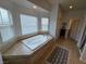 A bright bathroom with a corner bathtub is surrounded by large windows with tiled mosaic accents at 412 Orchid Oasis Ave, North Las Vegas, NV 89031