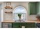 Kitchen sink beneath a unique arched window plus floating shelves and green cabinets at 412 Orchid Oasis Ave, North Las Vegas, NV 89031