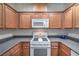 Bright kitchen featuring wood cabinets, white appliances, and gray countertops at 4725 Basilicata Ln # 204, North Las Vegas, NV 89084