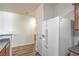Bright kitchen with white refrigerator, wood floors, and a glimpse into the adjacent bathroom at 4725 Basilicata Ln # 204, North Las Vegas, NV 89084