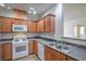 Galley kitchen featuring wood cabinets, stainless steel sink, and white appliances at 4725 Basilicata Ln # 204, North Las Vegas, NV 89084