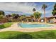 Community pool surrounded by lounge chairs, grassy areas, and mature palm trees at 5751 E Hacienda Ave # 154, Las Vegas, NV 89122