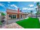 Expansive backyard featuring artificial turf, covered patio, a pergola, and mature palm trees at 6508 Peppermill Dr, Las Vegas, NV 89146